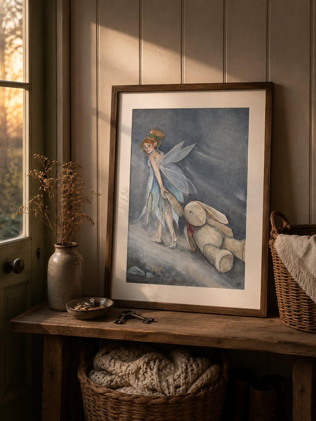 Framed Oona and the Rabbit fairy art print in a warm cottage entryway, with a basket of found keepsakes nearby.