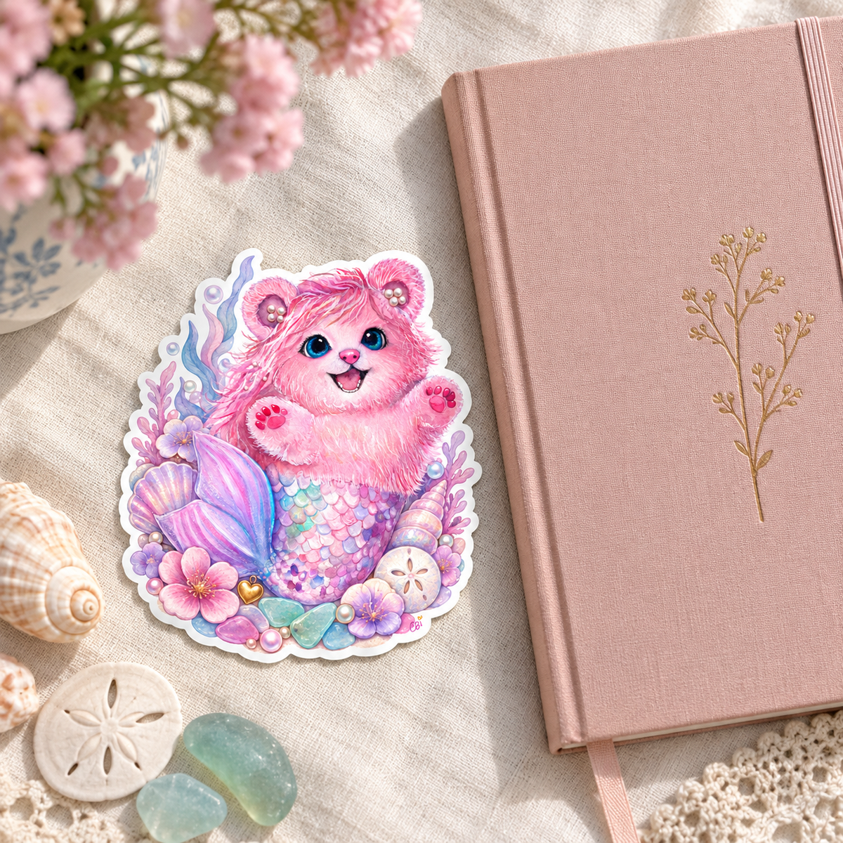 Pearl shell garden sticker on cream linen beside a pink journal, shells and sea glass.