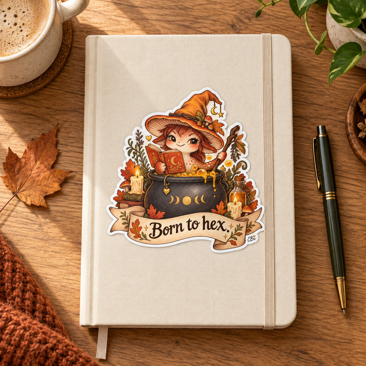 Born to Hex sticker on a cream journal on a cozy wooden desk.