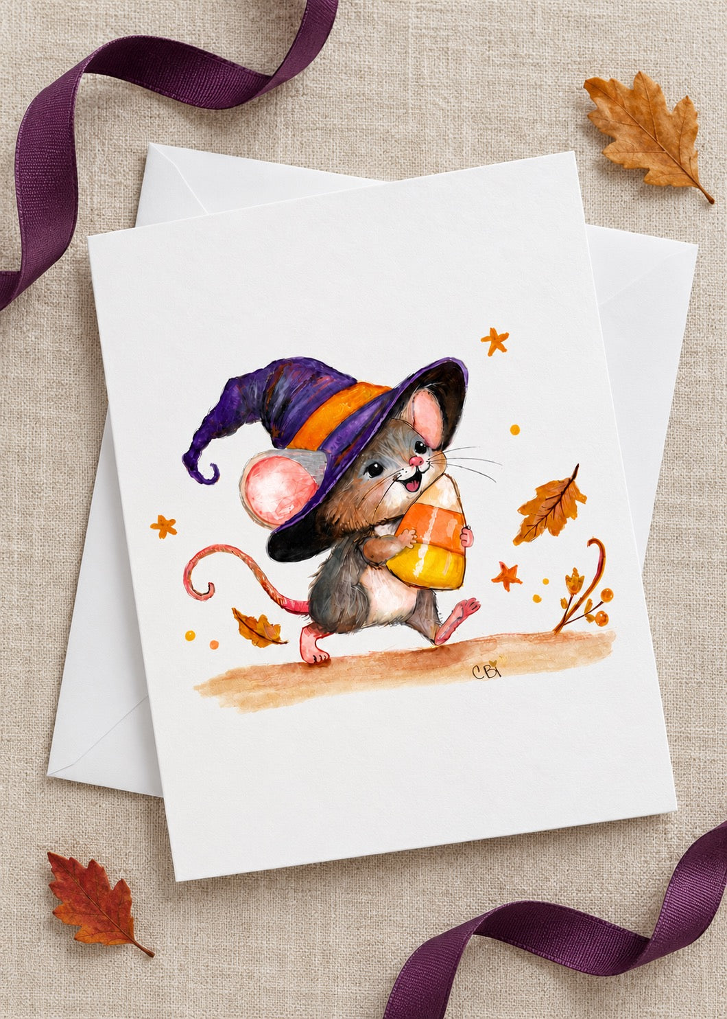 Candy Corn Mischief greeting card and white envelope on linen with plum ribbon and autumn leaves.