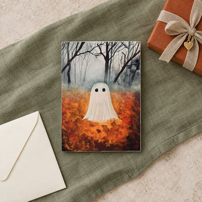 Fall Ghost greeting card on sage linen beside a rust-colored wrapped gift and ivory envelope.