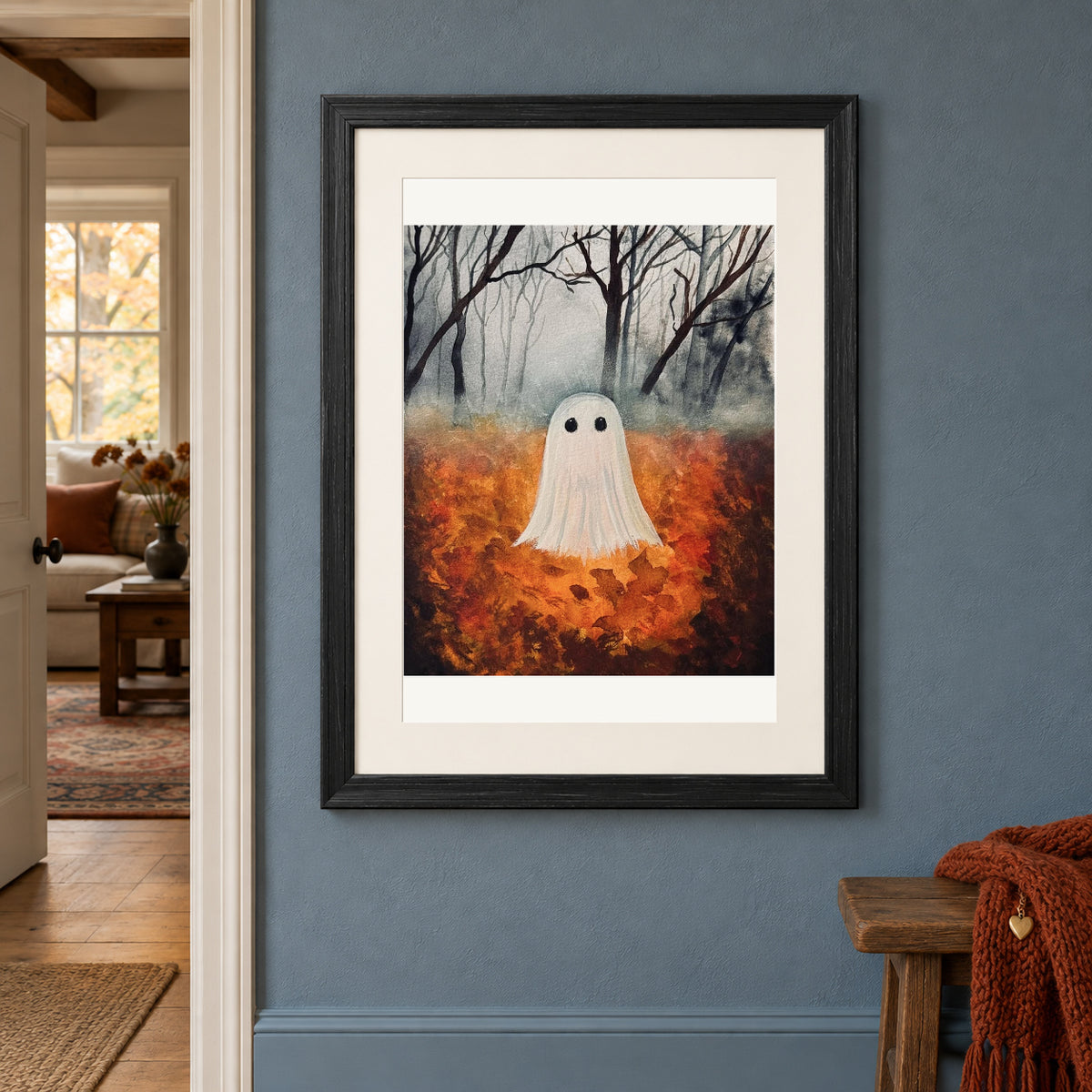 Fall Ghost print in a black frame on a blue hallway wall beside a doorway and a bench with a rust scarf.