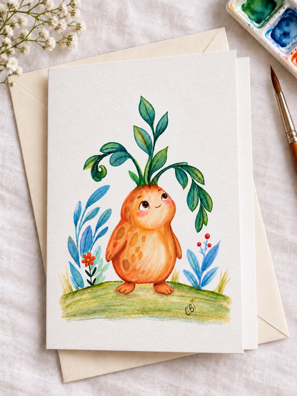 Figment greeting card with artwork inset within white margins and a simple left-side fold, on an envelope beside painting supplies.