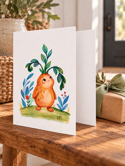 Figment greeting card with artwork inset within white margins and a simple left-side fold, beside a wrapped gift.