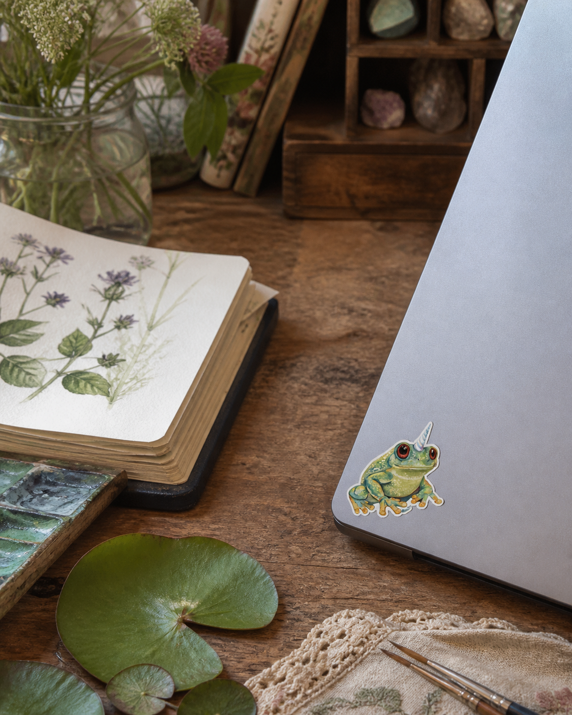 Froggicorn vinyl sticker on a laptop in a botanical art studio