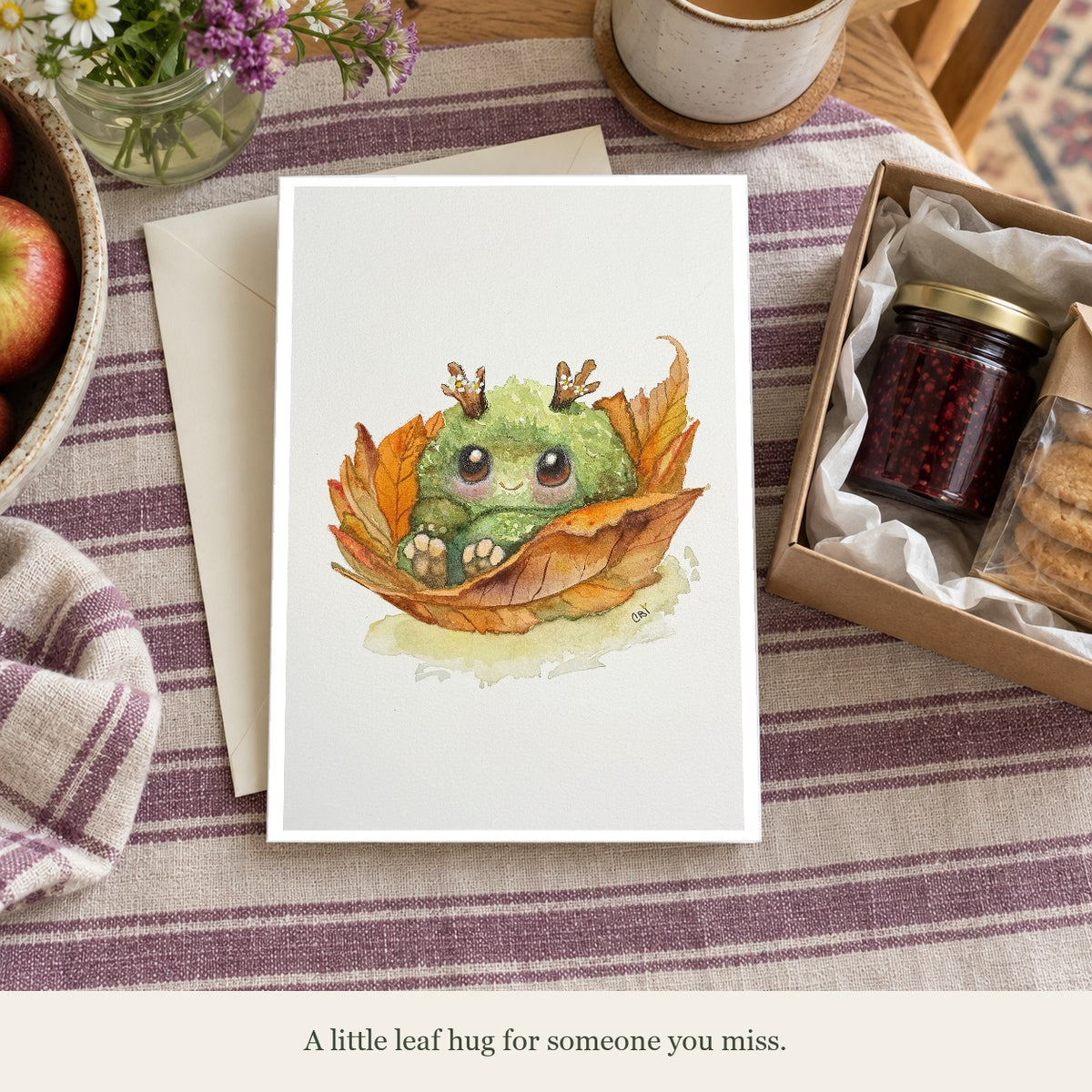 Fall Mossling card beside a care package. Caption: A little leaf hug for someone you miss. Gift props are not included.