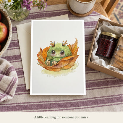 Fall Mossling card beside a care package. Caption: A little leaf hug for someone you miss. Gift props are not included.