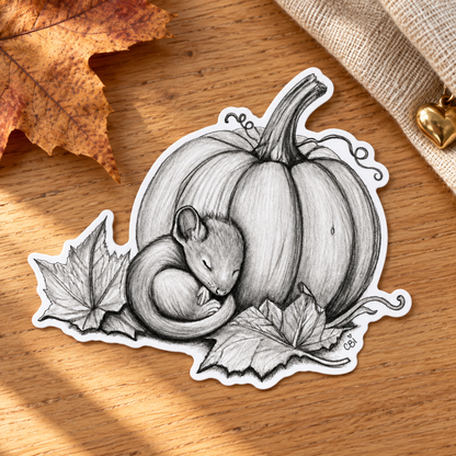 Close-up of the Sleeping Mouse and Pumpkin sticker on oak beside a maple leaf and linen.