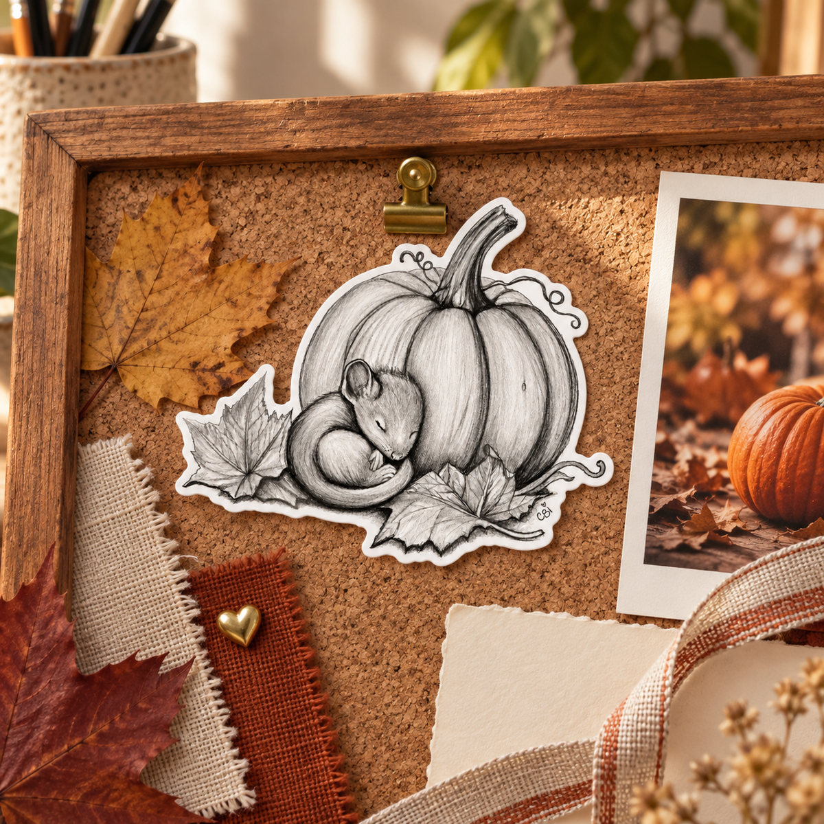 Sleeping Mouse and Pumpkin sticker on an autumn cork inspiration board with leaves, fabric swatches, and a pumpkin photograph.